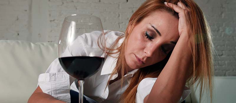 грустная женщина сидит рядом с бокалом вина
